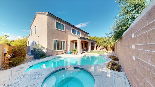 rear view of house featuring a pool with hot tub and a patio