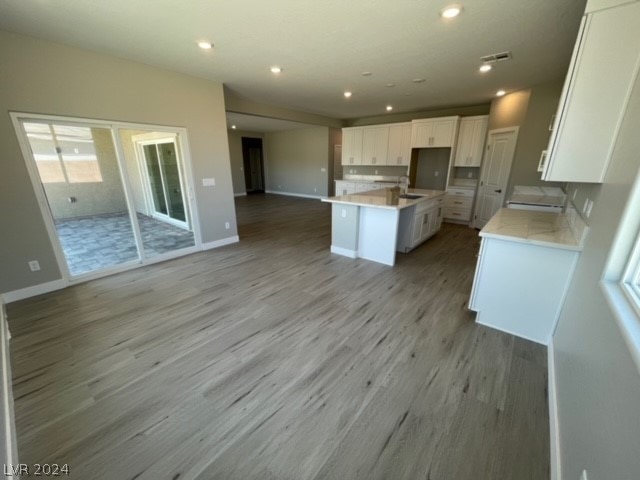 kitchen with white cabinetry, a center island, wood-type flooring, and sink