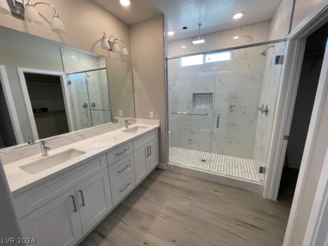 bathroom with dual vanity, a shower with shower door, and hardwood / wood-style floors