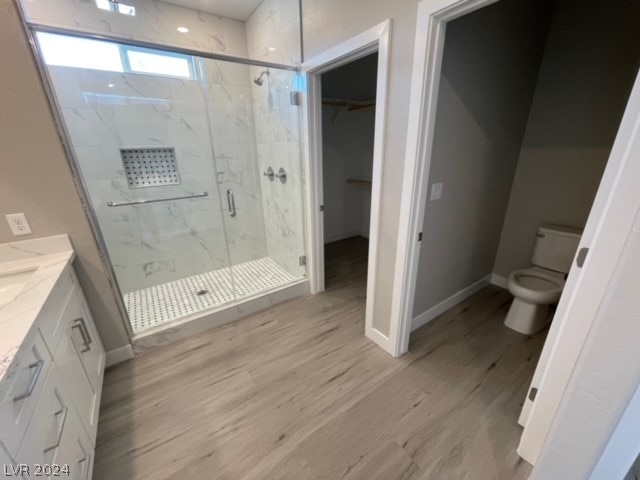 bathroom featuring walk in shower, wood-type flooring, toilet, and vanity