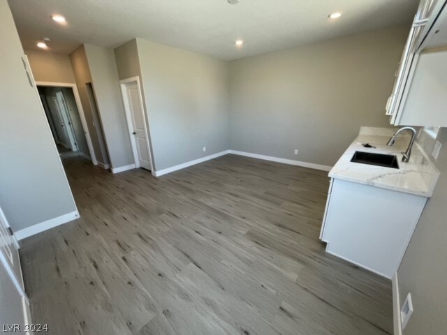 kitchen with sink, light stone counters, and wood-type flooring