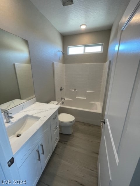 full bathroom with a textured ceiling, toilet, vanity, wood-type flooring, and bathing tub / shower combination