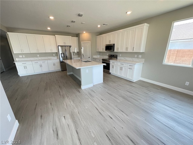 kitchen with white cabinetry, light hardwood / wood-style flooring, appliances with stainless steel finishes, and an island with sink