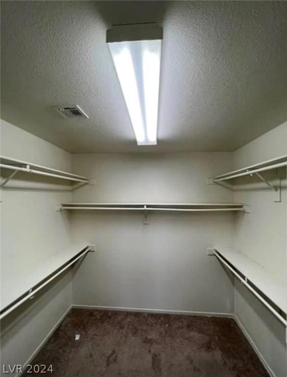 spacious closet featuring dark carpet