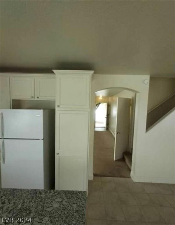 kitchen with dark stone countertops, white fridge, and white cabinets