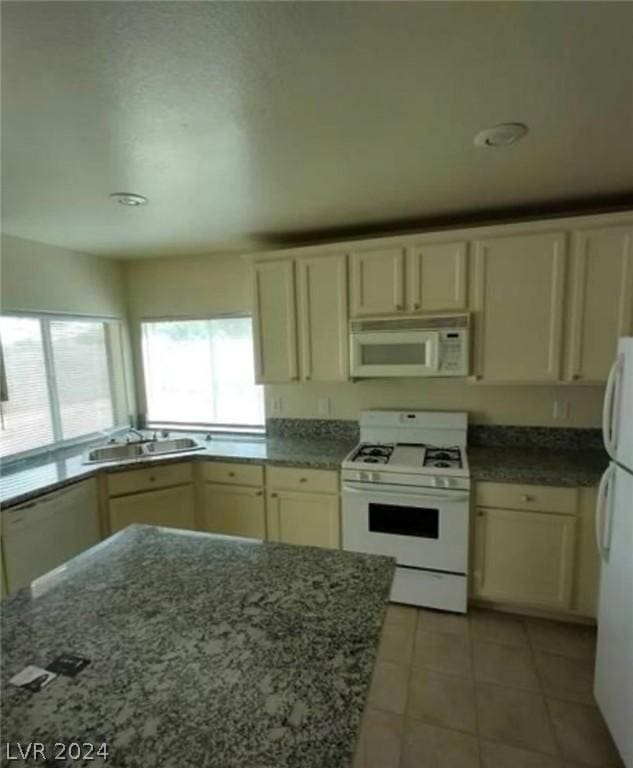 kitchen featuring light tile patterned flooring, cream cabinets, sink, and white appliances