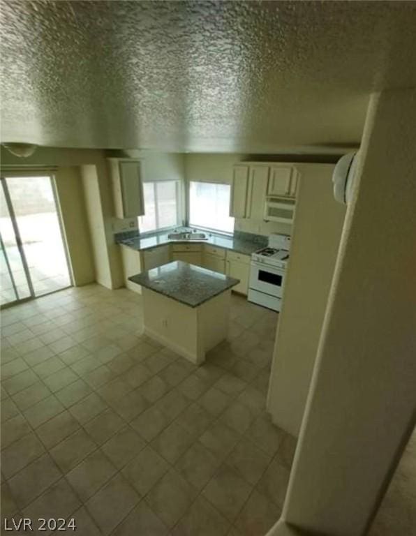 kitchen with sink, white cabinetry, a center island, a textured ceiling, and white appliances