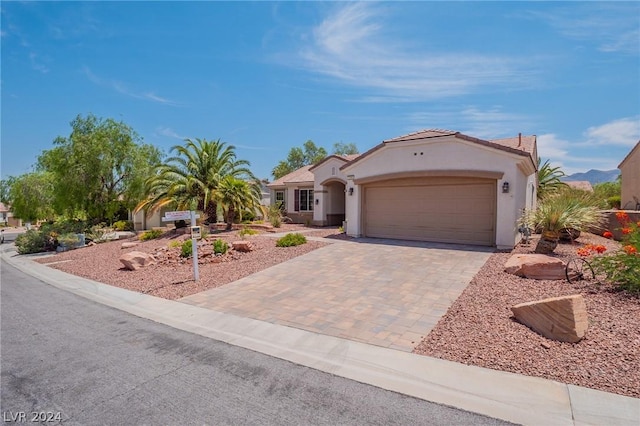 mediterranean / spanish-style house featuring stucco siding, a mountain view, decorative driveway, and a garage