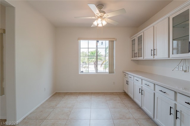 interior space with white cabinets, light tile patterned floors, light stone countertops, and ceiling fan