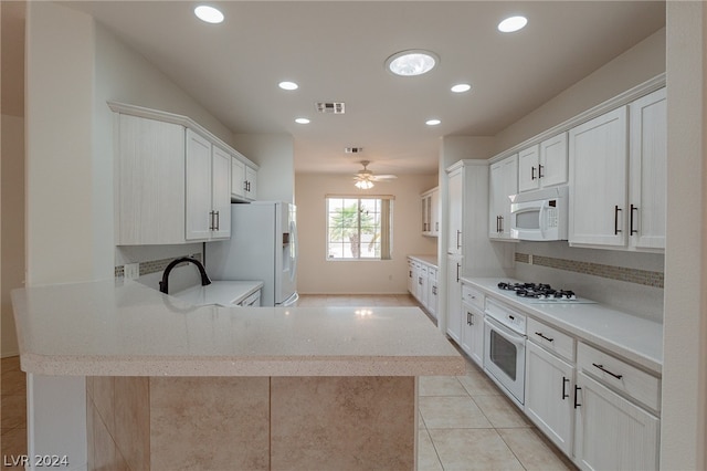 kitchen with decorative backsplash, kitchen peninsula, white appliances, light tile patterned floors, and white cabinets