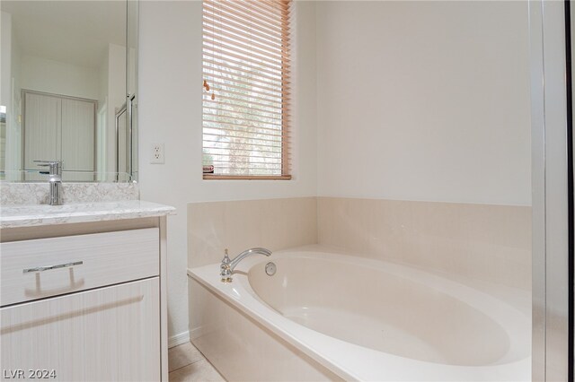 bathroom featuring tile patterned flooring, vanity, and a tub to relax in