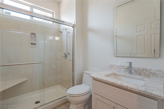 bathroom featuring tile patterned floors, vanity, a shower with shower door, and toilet