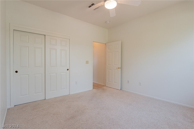 unfurnished bedroom with ceiling fan, a closet, and light colored carpet