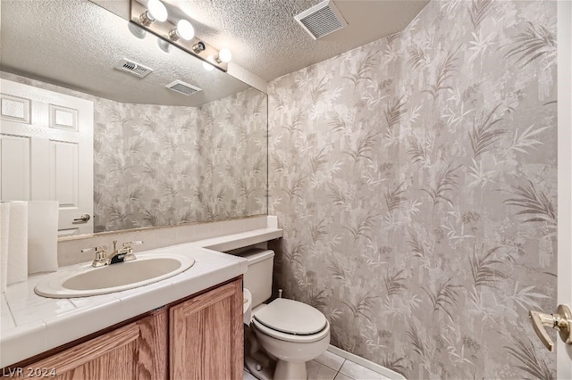 bathroom with vanity, toilet, tile patterned flooring, and a textured ceiling