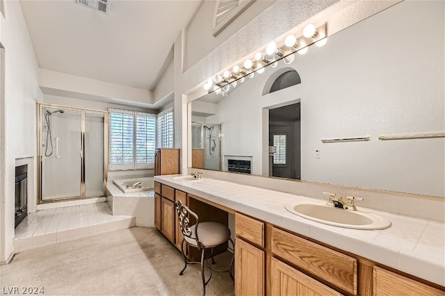 bathroom with lofted ceiling, vanity, and independent shower and bath