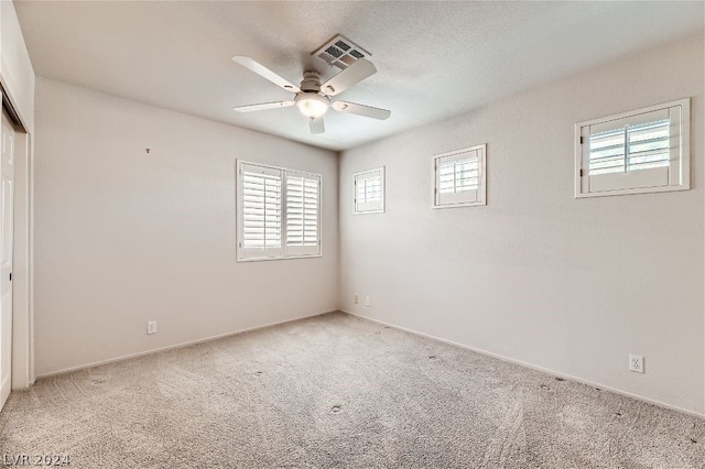 carpeted empty room with a textured ceiling and ceiling fan