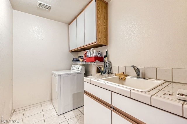 washroom featuring light tile patterned flooring, cabinets, washer / clothes dryer, and sink