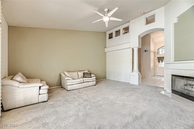 unfurnished living room with a tiled fireplace, a towering ceiling, light carpet, and ceiling fan