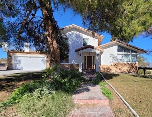 view of front of home with stucco siding, concrete driveway, a front yard, and a garage