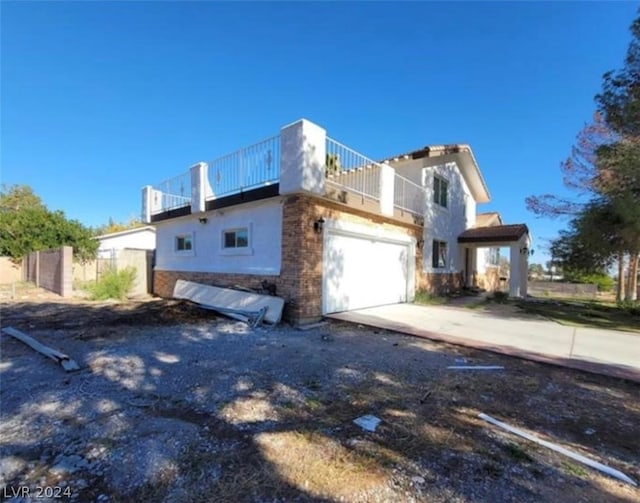 view of side of property featuring a balcony, a garage, and stucco siding