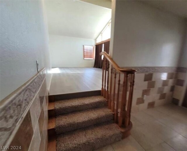 stairs featuring lofted ceiling and hardwood / wood-style flooring