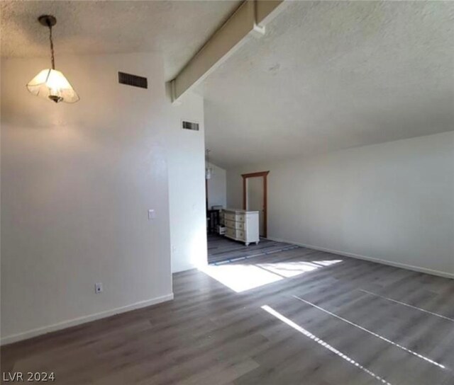 unfurnished living room featuring lofted ceiling with beams, dark hardwood / wood-style flooring, and a textured ceiling