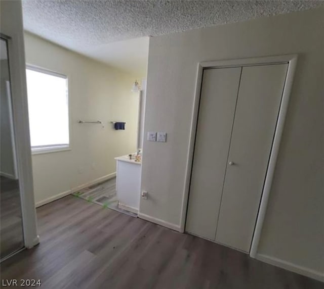 unfurnished bedroom with a textured ceiling, dark hardwood / wood-style floors, and a closet