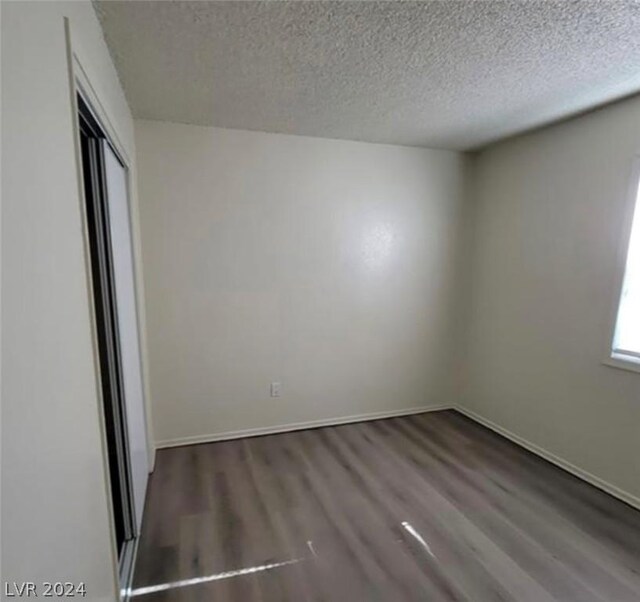 spare room featuring wood-type flooring and a textured ceiling