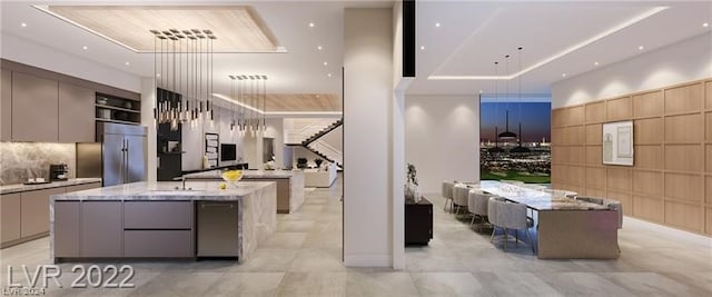 kitchen with stainless steel appliances, gray cabinets, light stone counters, light tile floors, and a center island