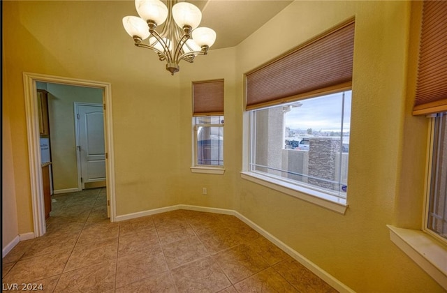 tiled empty room featuring an inviting chandelier