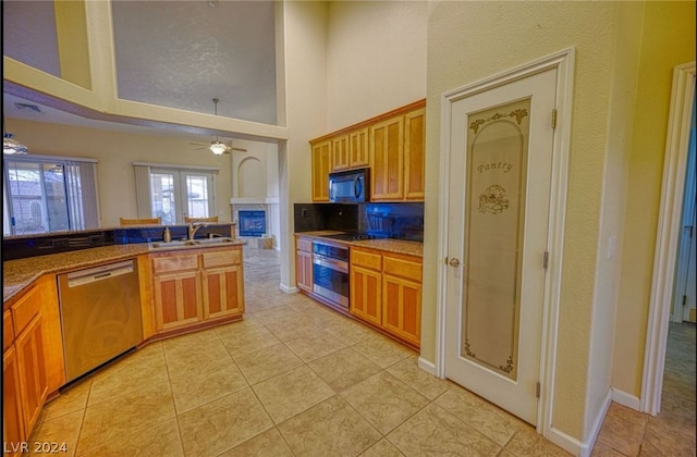 kitchen with black appliances, a towering ceiling, sink, tasteful backsplash, and ceiling fan