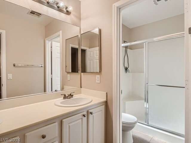 bathroom with a shower with shower door, tile flooring, vanity, and toilet