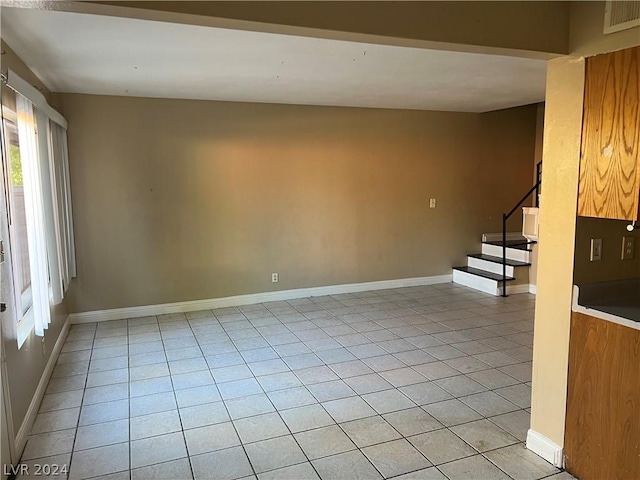 spare room featuring stairway, light tile patterned flooring, visible vents, and baseboards