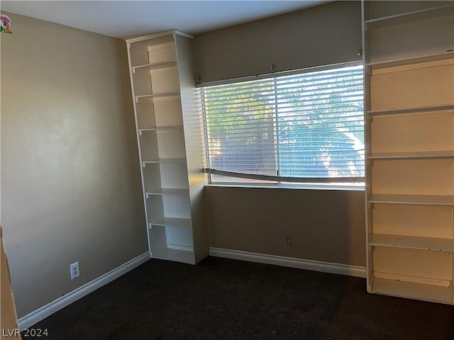 interior space with baseboards and dark colored carpet