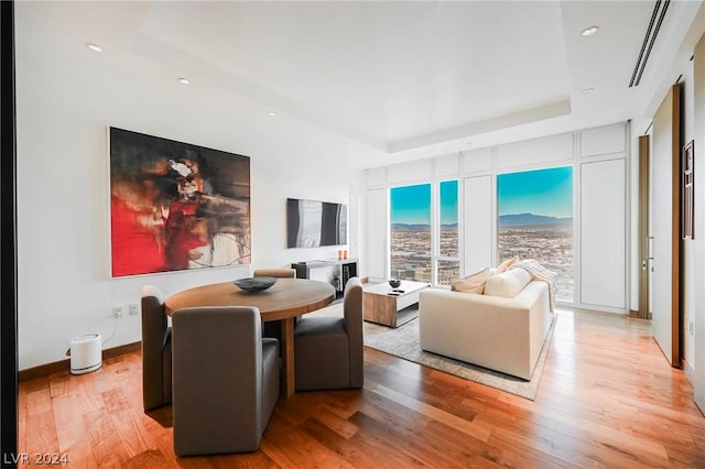 living room featuring a tray ceiling and light hardwood / wood-style floors