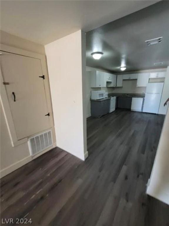 interior space featuring white refrigerator, white cabinetry, and dark hardwood / wood-style flooring