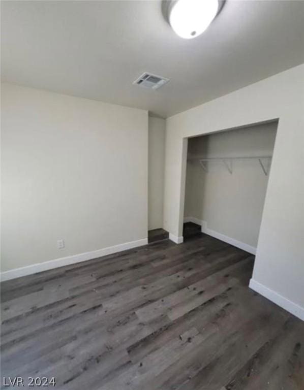 unfurnished bedroom featuring dark wood-type flooring and a closet