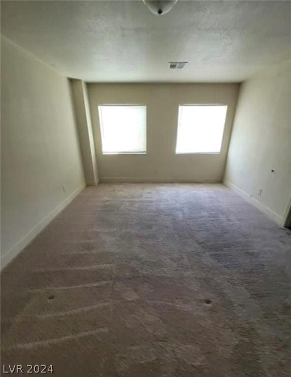 spare room with dark colored carpet and a healthy amount of sunlight