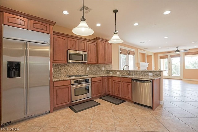 kitchen with sink, hanging light fixtures, light tile patterned floors, appliances with stainless steel finishes, and decorative backsplash