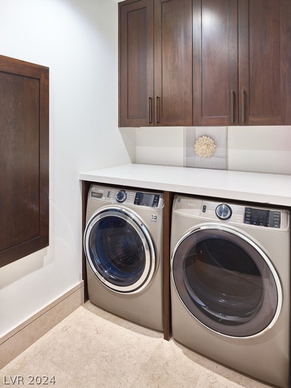 clothes washing area featuring washing machine and clothes dryer, cabinets, and light tile patterned floors