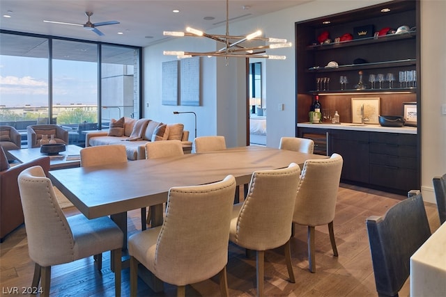 dining room featuring sink, light wood-type flooring, expansive windows, and ceiling fan with notable chandelier