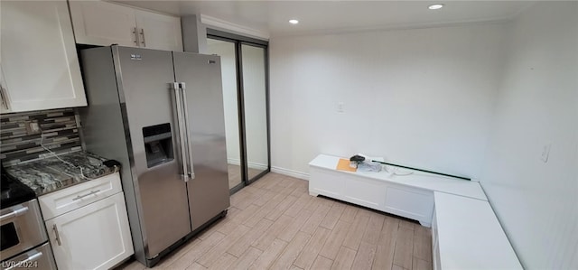 kitchen featuring light hardwood / wood-style flooring, white cabinets, high end refrigerator, and decorative backsplash