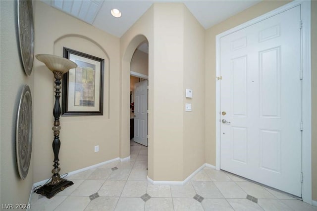 foyer entrance featuring arched walkways, recessed lighting, baseboards, and light tile patterned floors