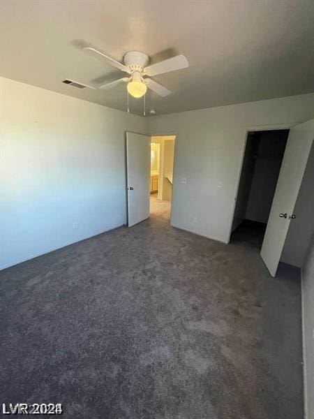 unfurnished bedroom with ceiling fan and dark colored carpet