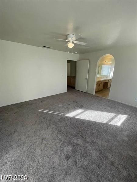 unfurnished bedroom featuring ceiling fan, ensuite bath, and carpet flooring