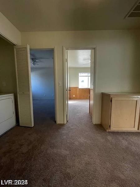 hallway with wooden walls, washer / dryer, and carpet flooring