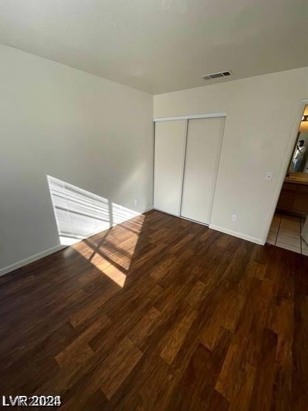 unfurnished bedroom with dark wood-type flooring and a closet