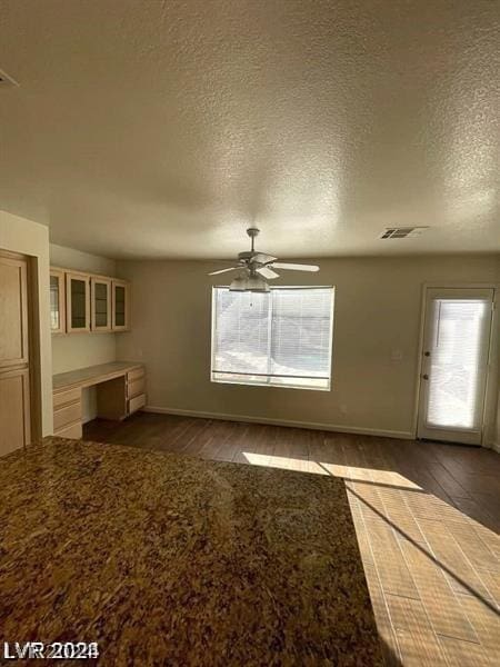 unfurnished living room featuring ceiling fan, plenty of natural light, and a textured ceiling