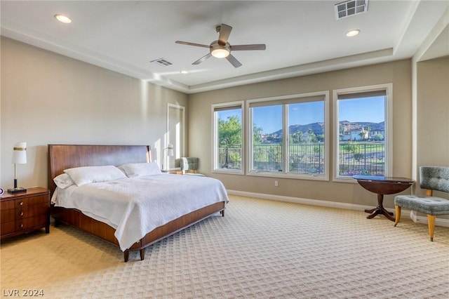 bedroom with a mountain view, ceiling fan, and light colored carpet