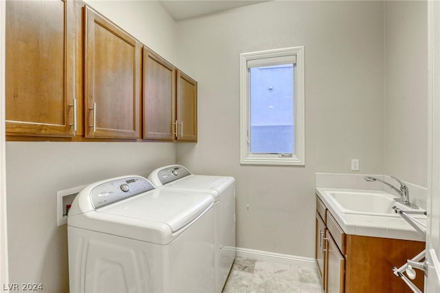 clothes washing area with washing machine and clothes dryer, sink, and cabinets